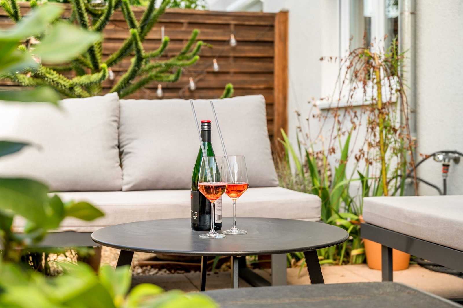 Gartenterrasse mit Lounge und einem Glas Rosé am Abend